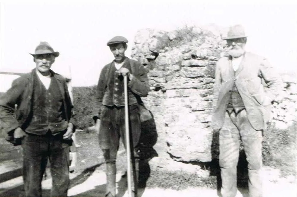 Archive photograph of farmers beside a stone wall