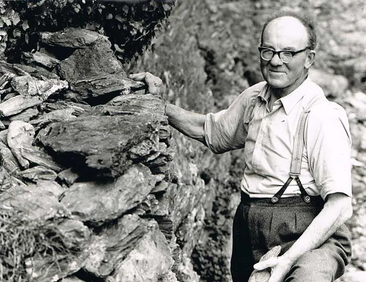 Archive photograph of Mr John Tucker beside a stone wall