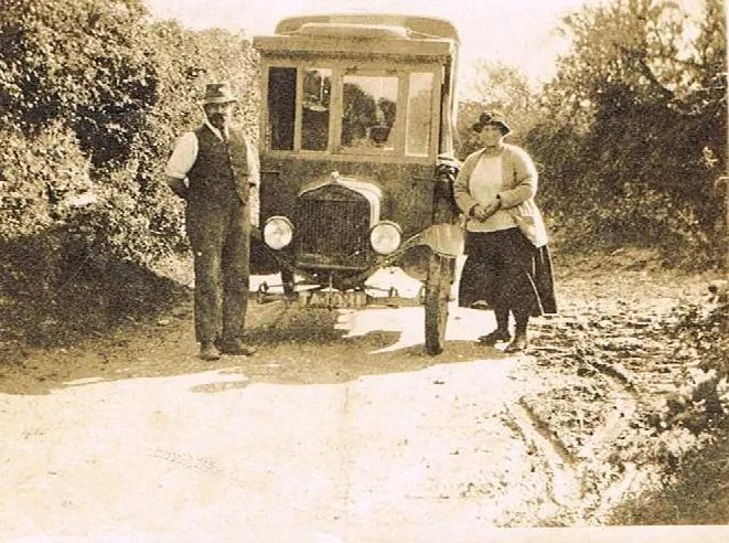 Archive photograph of a couple standing beside an early motor car