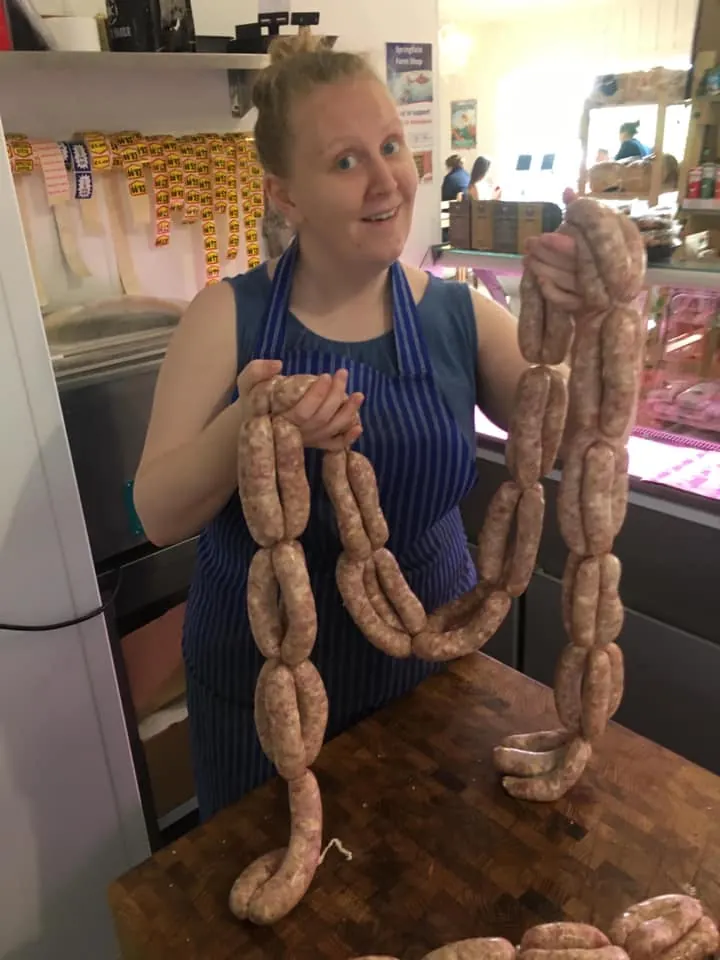 Holding up a long string of freshly made sausages