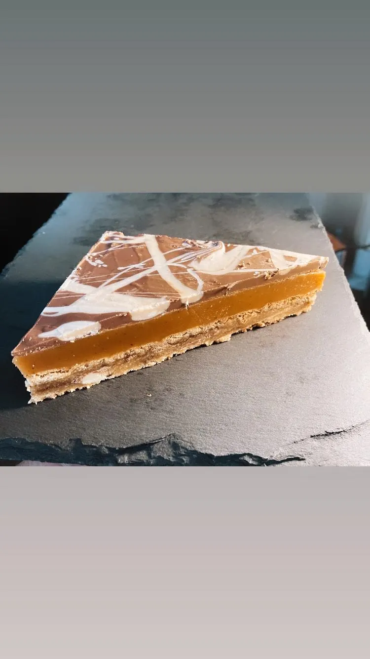 A slice of millionaire cookie dough on the counter